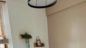 A neatly made bed with white linens and two folded towels, a bedside lamp, a wall-mounted shelf with a plant and picture, and a window with blinds. - Modern City Center 2 Bedroom Apartment (Aberdeen)