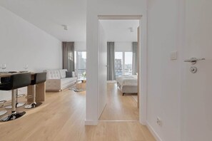 Una habitación de hotel moderna con comedor, sofá, cama y vistas a la ciudad.