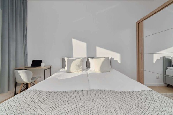 Un dormitorio moderno con una cama grande, un escritorio y una silla.