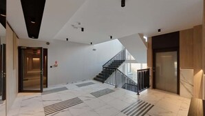 A spacious lobby with a marble floor, a staircase, and a door leading to another area. - Modern Apartment | Parking, Balcony, Workspace (Wroclaw)