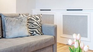 A living room with a grey sofa, a vase with flowers, and a fireplace.