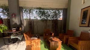 Een kamer met houten meubels, een vloer van kunstgras en een raam met bamboe buiten.