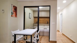 A modern room with a dining area, a bed, and a wooden panel wall.