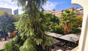 Un patio con un árbol grande, mobiliario exterior y vistas a edificios residenciales.