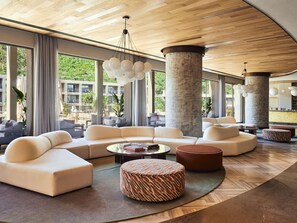 A spacious lobby with a modern design, featuring a large seating area, a central column, and large windows offering a view of the outdoors. - Hyde Bodrum - Adults Only - All Inclusive (Bodrum)