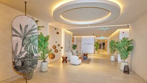 Un hall d’hôtel moderne doté d’un espace salon central, de plantes en pot et d’un plafond au design circulaire.