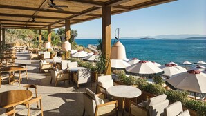 Un espace extérieur aménagé avec des tables, des chaises, des parasols et une vue sur la mer.