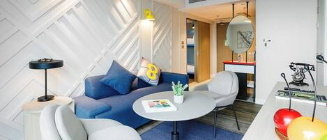 Una sala de estar moderna con un sofá, sillones, una mesa de centro y un comedor con un objeto esférico rojo y amarillo.