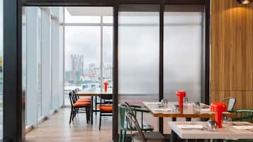 A modern dining area with large windows, wooden accents, and a city view.