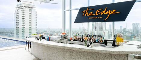 A bar named "The Edge" with a city view, a pool, and a high ceiling.