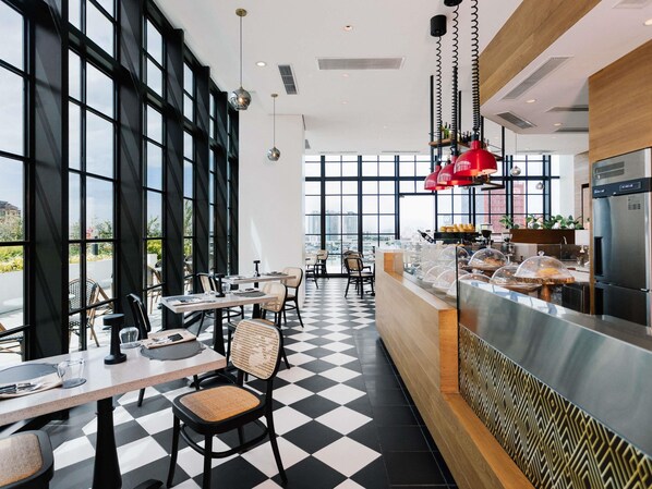 A modern restaurant with large windows, checkered flooring, and a counter with food display.