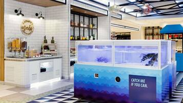 Un espacio interior moderno con piso a cuadros, una barra con frascos de aperitivos y una vitrina azul para peces.