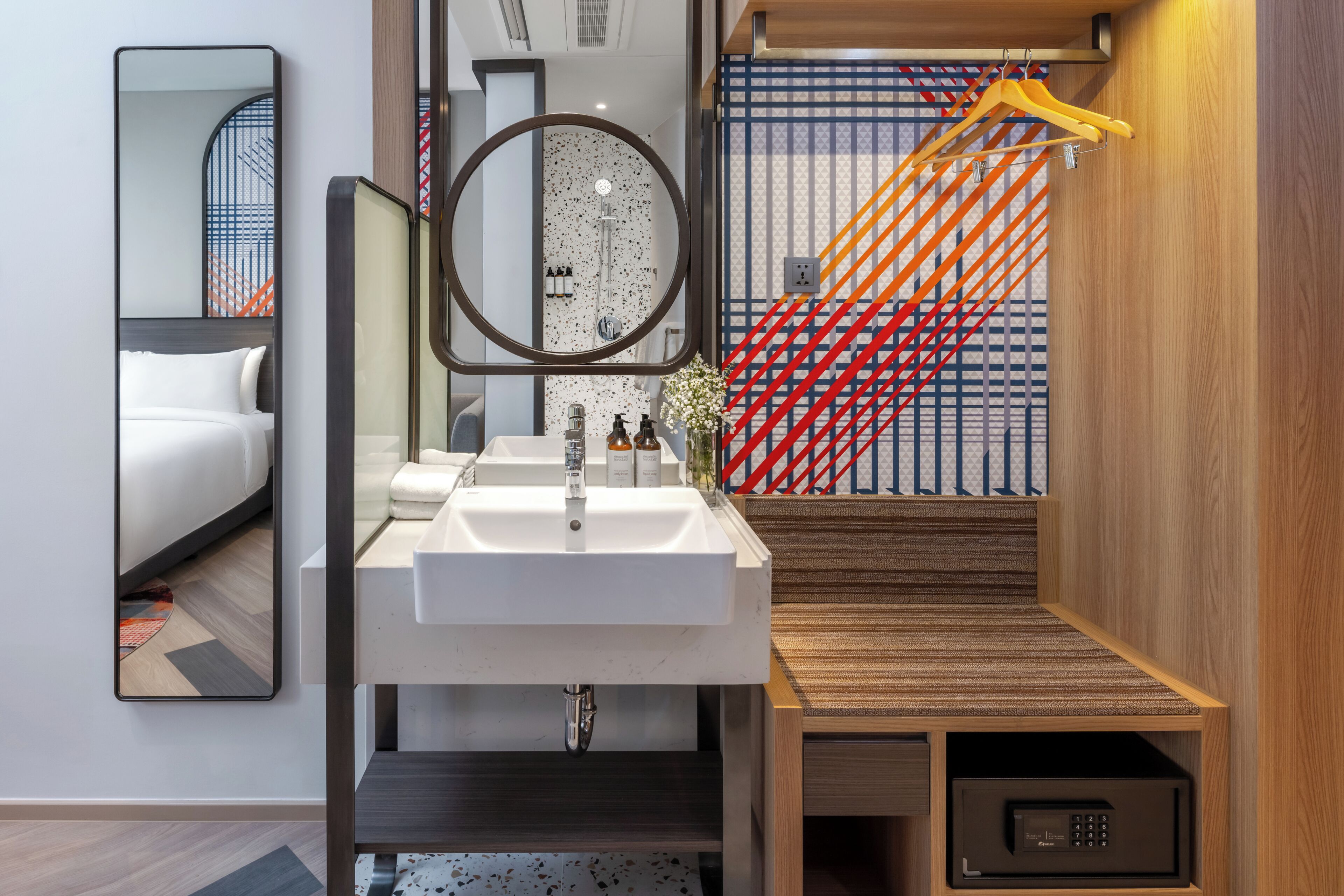 A modern bathroom with a white sink, mirror, and a wooden vanity.