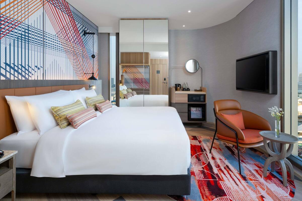 Une chambre d’hôtel moderne équipée d’un grand lit, d’un bureau, d’une chaise et d’un téléviseur.