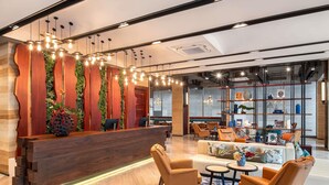A modern reception area with a wooden reception desk, seating area with leather chairs, and a wall with shelves displaying various items.