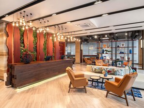 Een moderne receptiezone met een houten receptiebalie, een zithoek met lederen fauteuils, en een wand met planken waarop diverse objecten staan.