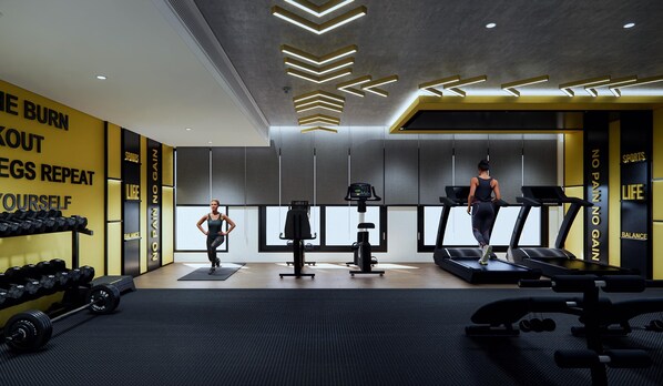 Een fitnessruimte met loopbanden, gewichten en een muur met motiverende tekst.