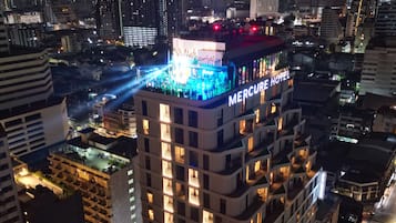 Ein Hochhotel mit mehreren Etagen, einer Dachterrasse und einer gut beleuchteten Fassade.