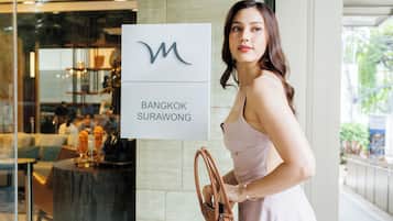 A woman standing next to a sign for Bangkok Surawong.