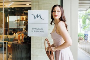 Une femme se tient à côté d’un panneau indiquant « Bangkok Surawong ».