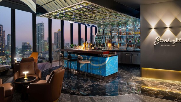 A rooftop bar with a city view, bar counter, seating area, and a decorative ceiling.