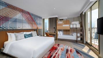 Habitación de hotel moderna con una cama grande, una cama litera, un escritorio y un televisor.
