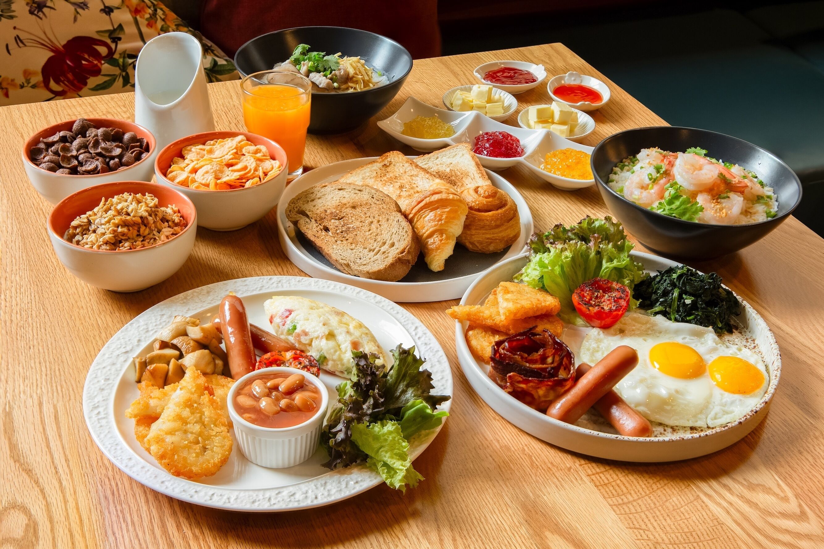 Un bufé de desayuno con diversas opciones, incluyendo tostadas, huevos, salchichas y una ensalada.