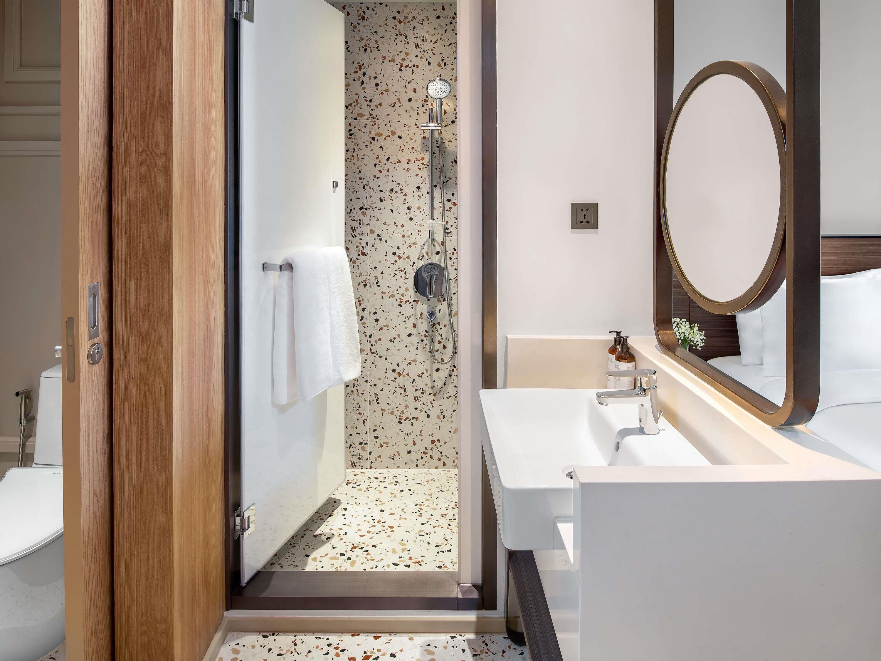 A modern bathroom with a shower, a sink, and a mirror.