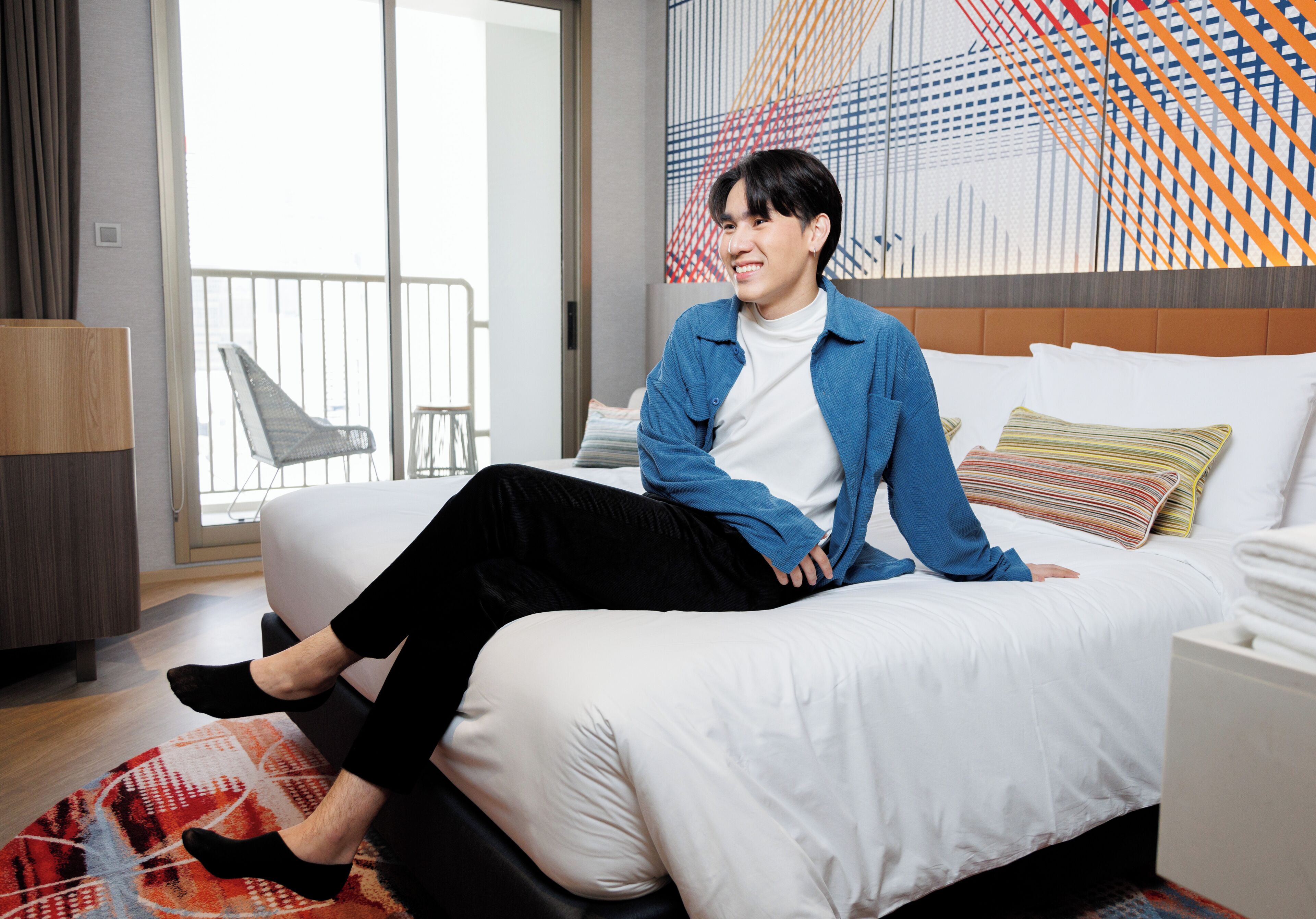 A hotel room with a bed, a window, and a view of the outside.
