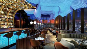 Un bar offrant une vue sur la ville, doté de sièges modernes et d’un design de plafond original.
