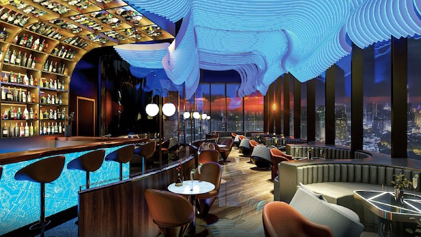 Een bar met uitzicht over de stad, modern meubilair en een uniek plafondontwerp.