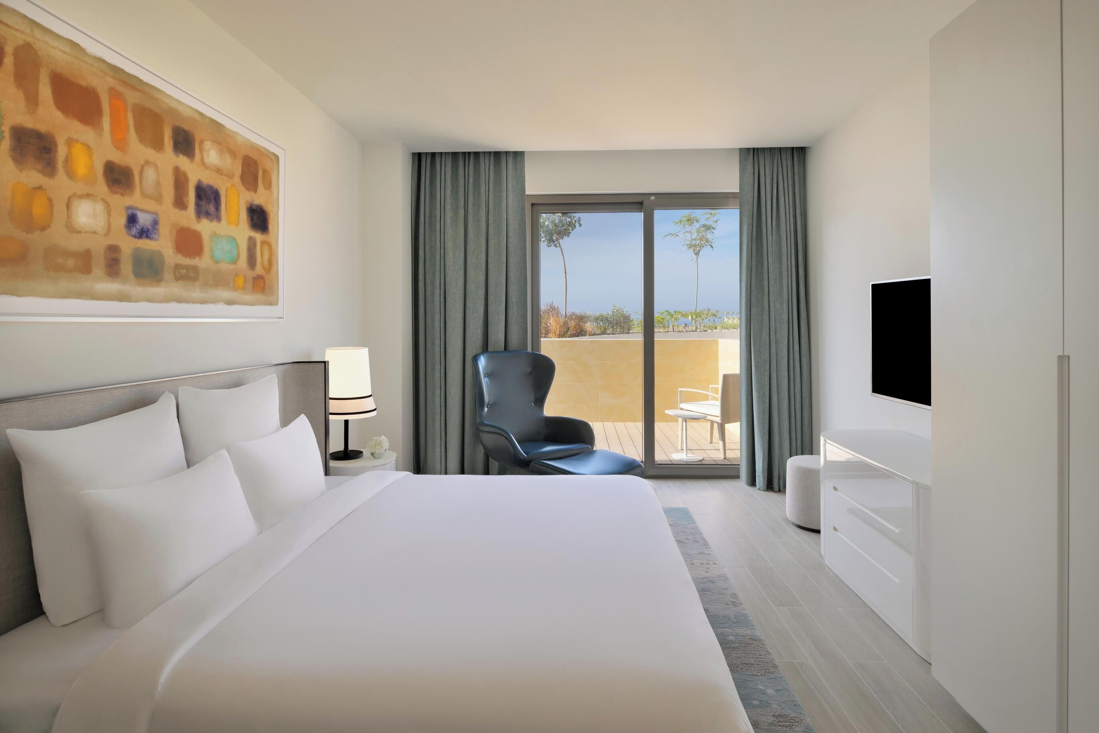 Habitación de hotel con una cama grande, televisión de pantalla plana, una silla y vistas al exterior.