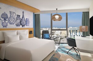Una habitación de hotel moderna con una cama grande, un escritorio y vistas a la ciudad.