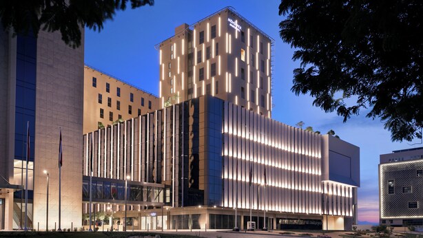 A modern hotel with a prominent tower, large windows, and a well-lit facade.