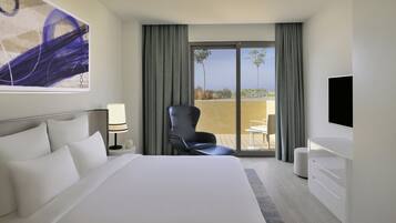 Une chambre d’hôtel avec un grand lit, une chaise, une télévision et un balcon avec vue.