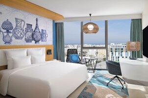 Una habitación de hotel moderna con una cama grande, un escritorio y vistas a la ciudad.