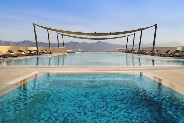 Een buitenzwembad, parasols bij het zwembad en ligstoelen