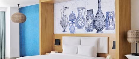 A modern hotel room with a large bed, a blue accent wall, and a wall art of vases.