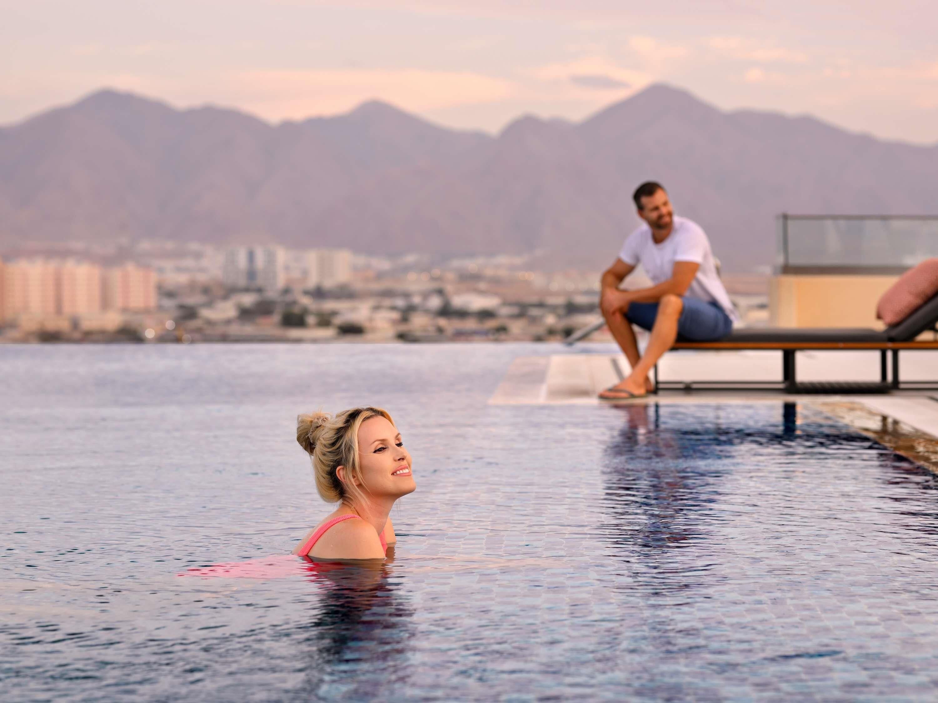 A pool area with a cityscape and mountains in the background.