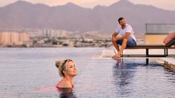 A pool area with a cityscape and mountains in the background.