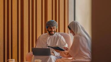 A room with a wooden panel wall, a table with a laptop, a cup, and a book.