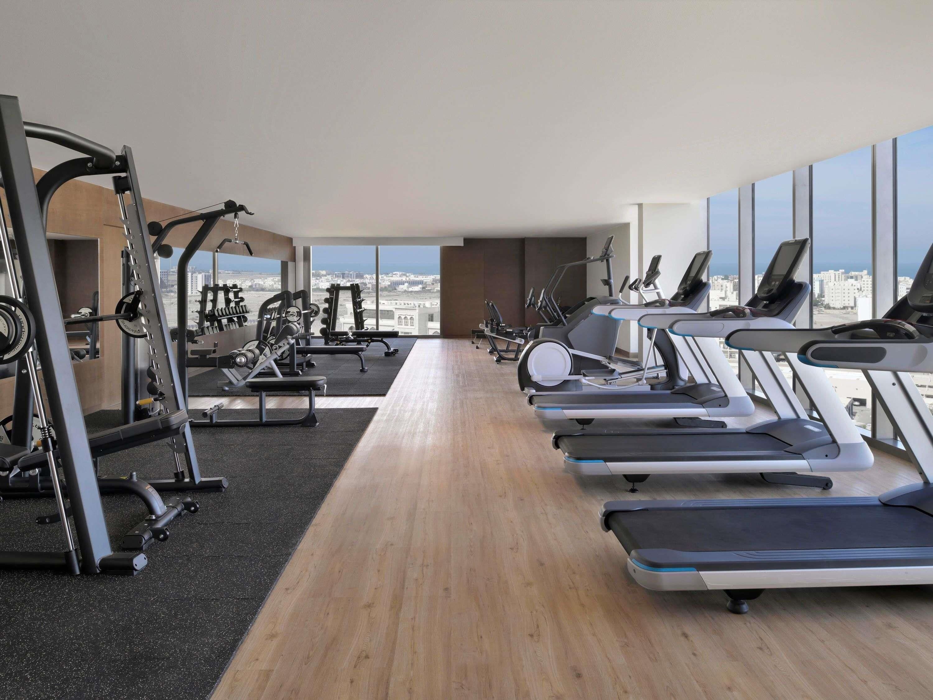 A gym with treadmills, weight machines, and a city view.