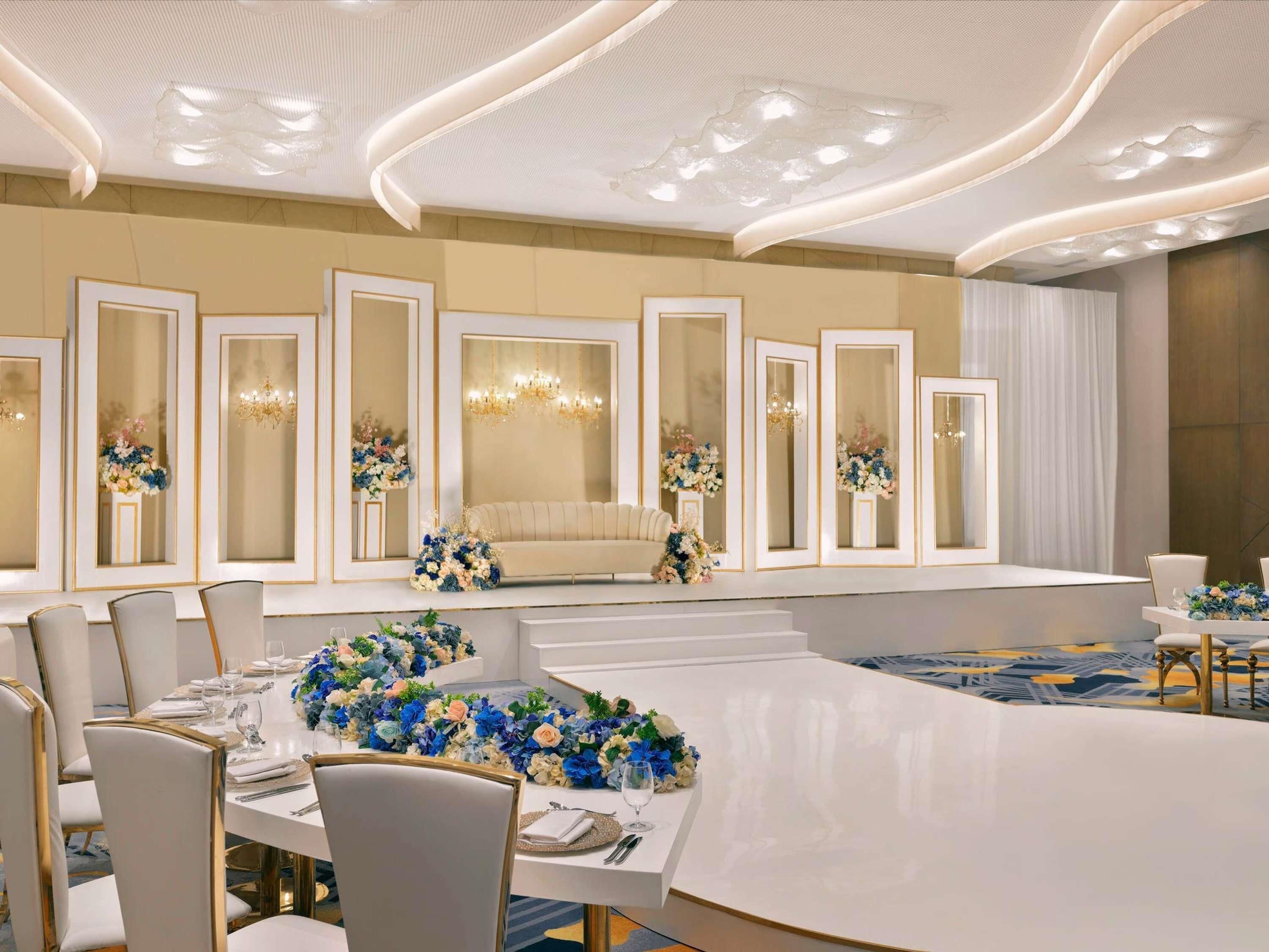 Ein formeller Speisesaal mit einem langen Tisch, mehreren Stühlen und dekorativen Blumenarrangements.