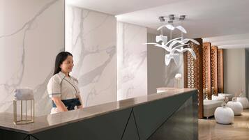 A reception area with a marble wall, a modern reception desk, and a decorative light fixture.