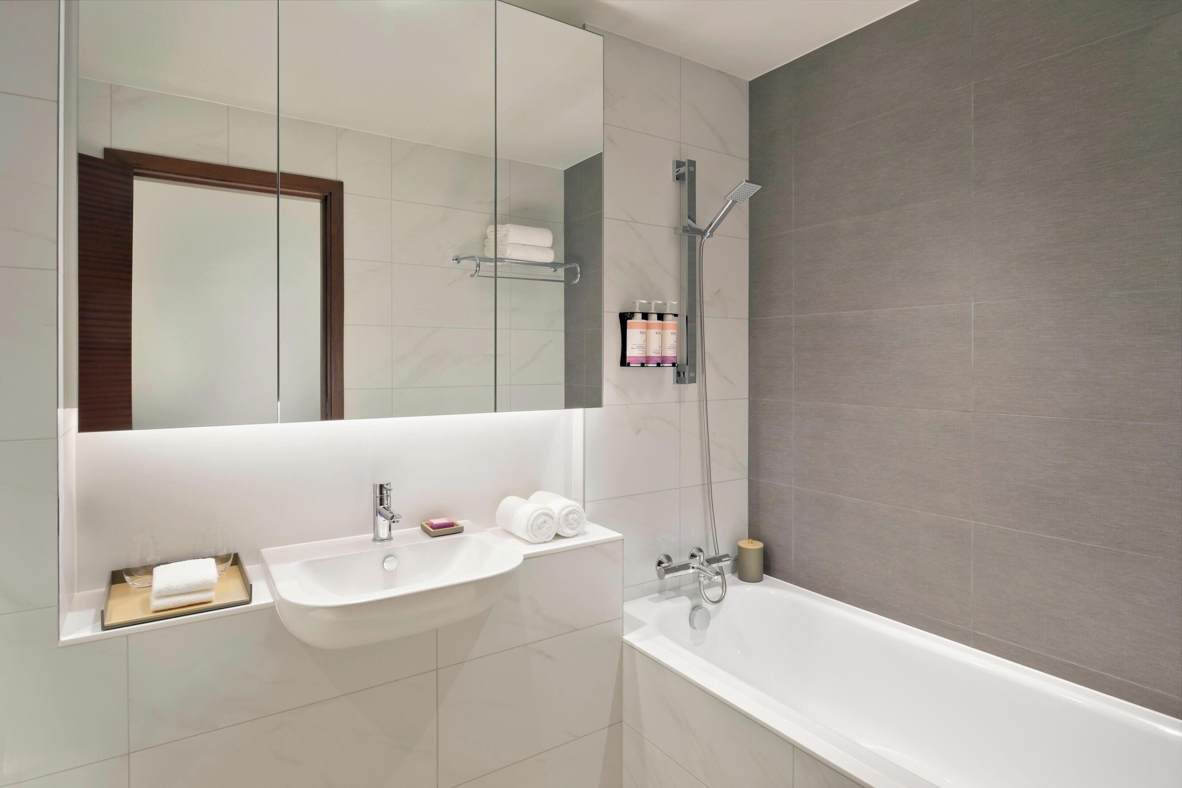 A modern bathroom with a white sink, a bathtub, and a glass-enclosed shower.