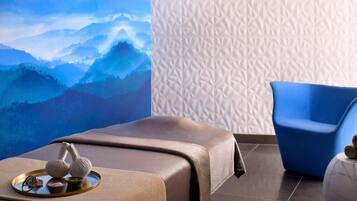 Relax in a serene spa room with a massage table, a comfortable chair, and a soothing mountain view.