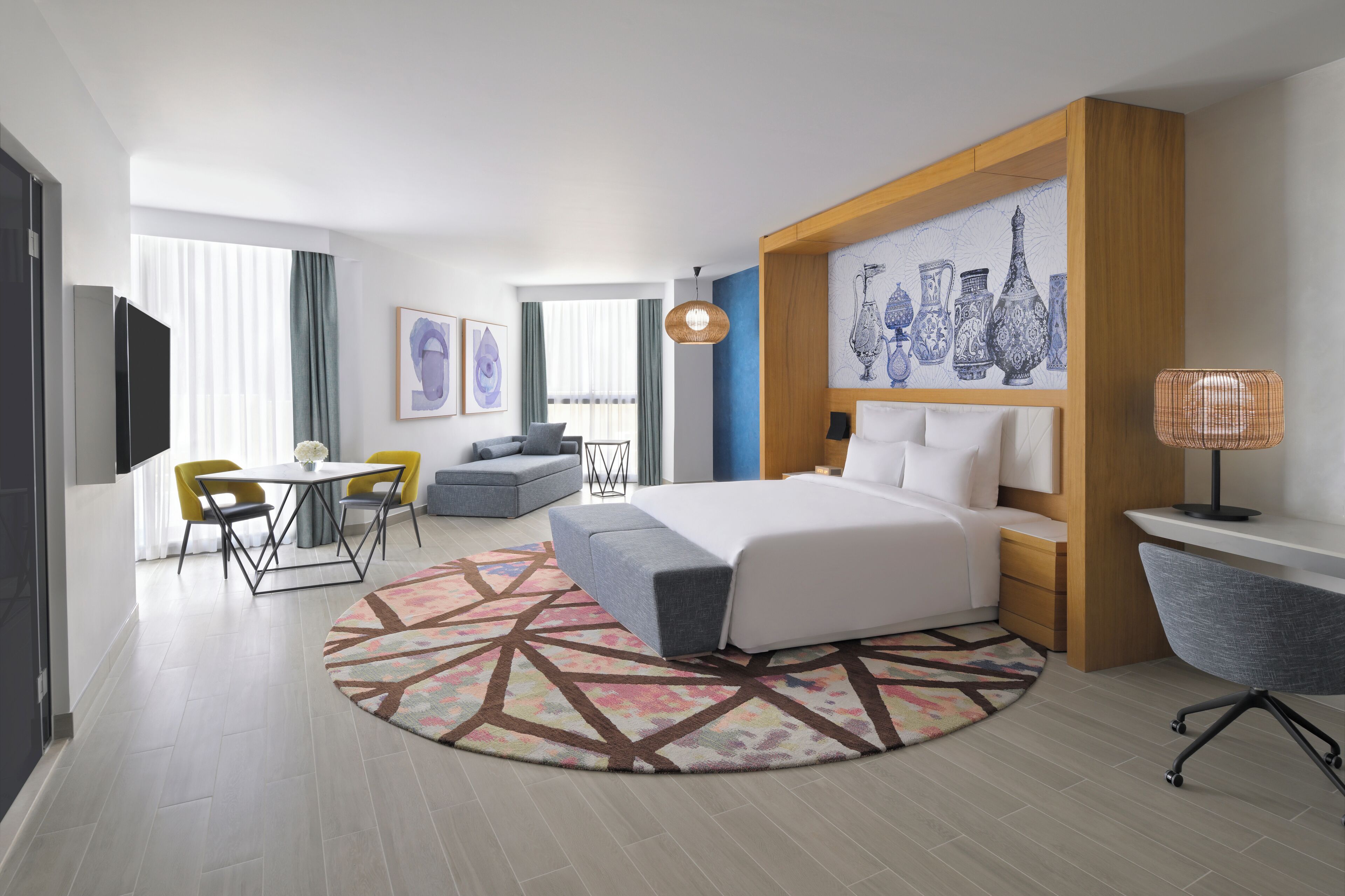 Una habitación de hotel moderna con cama, escritorio, silla, sofá y zona de comedor.