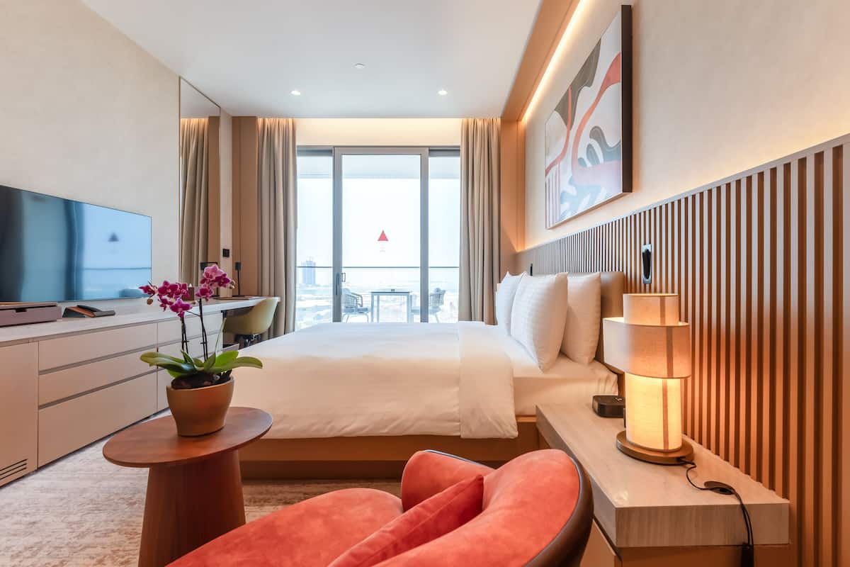 Une chambre d’hôtel moderne, dotée d’un grand lit, d’un bureau, d’une télévision et offrant une vue sur la ville.