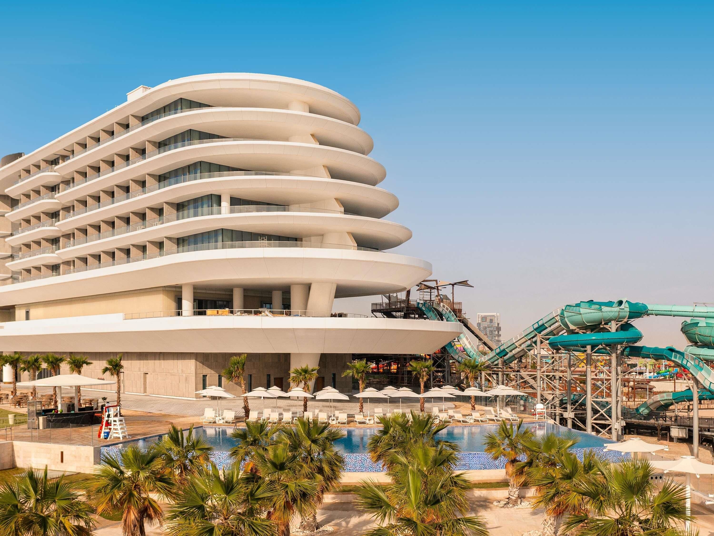 Un hotel moderno con una arquitectura curva distintiva, piscina y parque acuático.