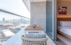 Relax on the balcony with a panoramic view of the city, featuring a table and chair for dining or unwinding.